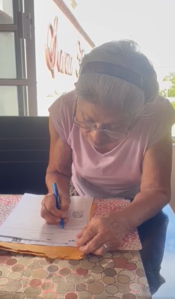 Abuelita firma papel sobre culminación de estudios